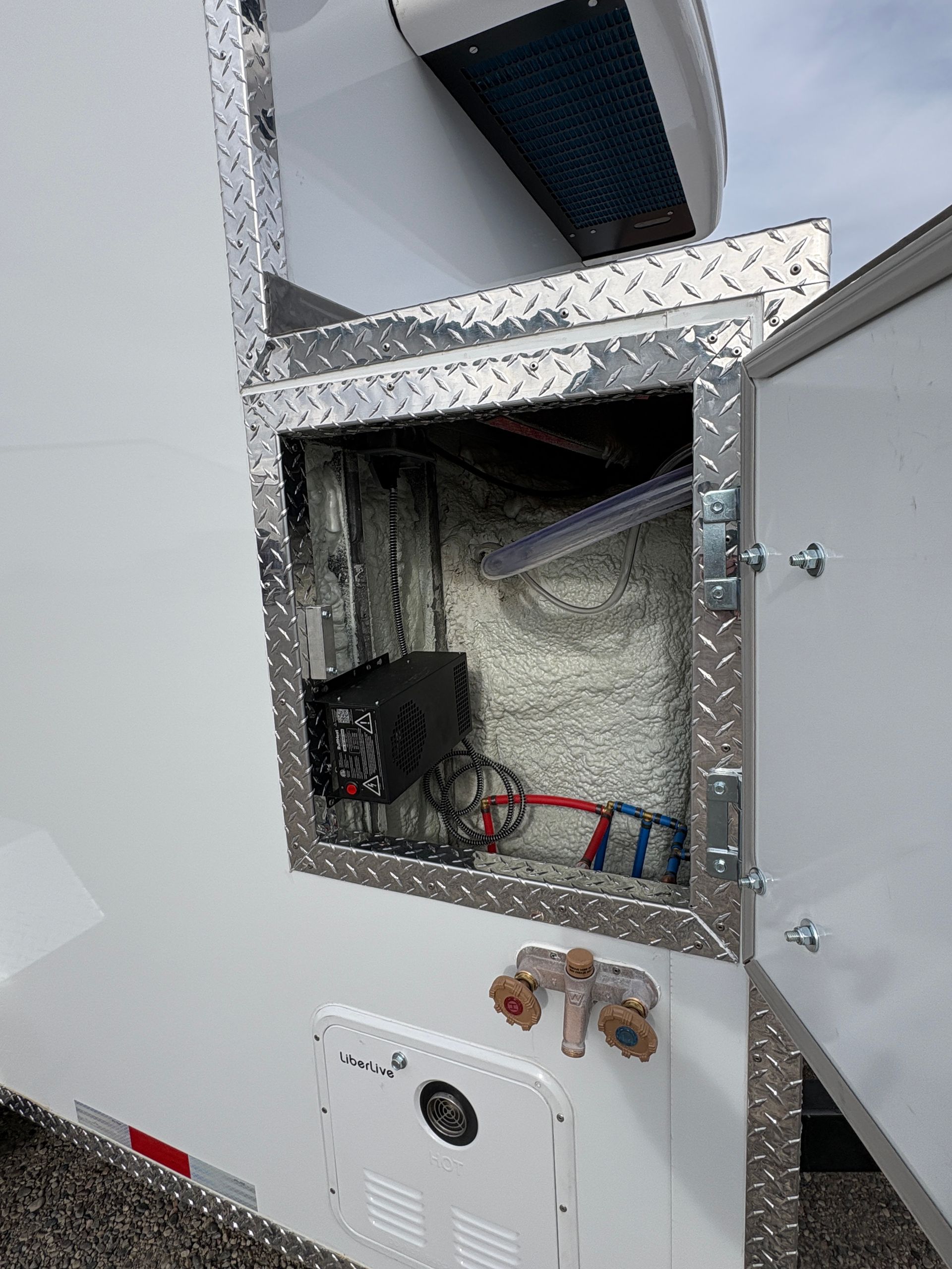 Open HVAC access panel with exposed wiring and ductwork in a wall.