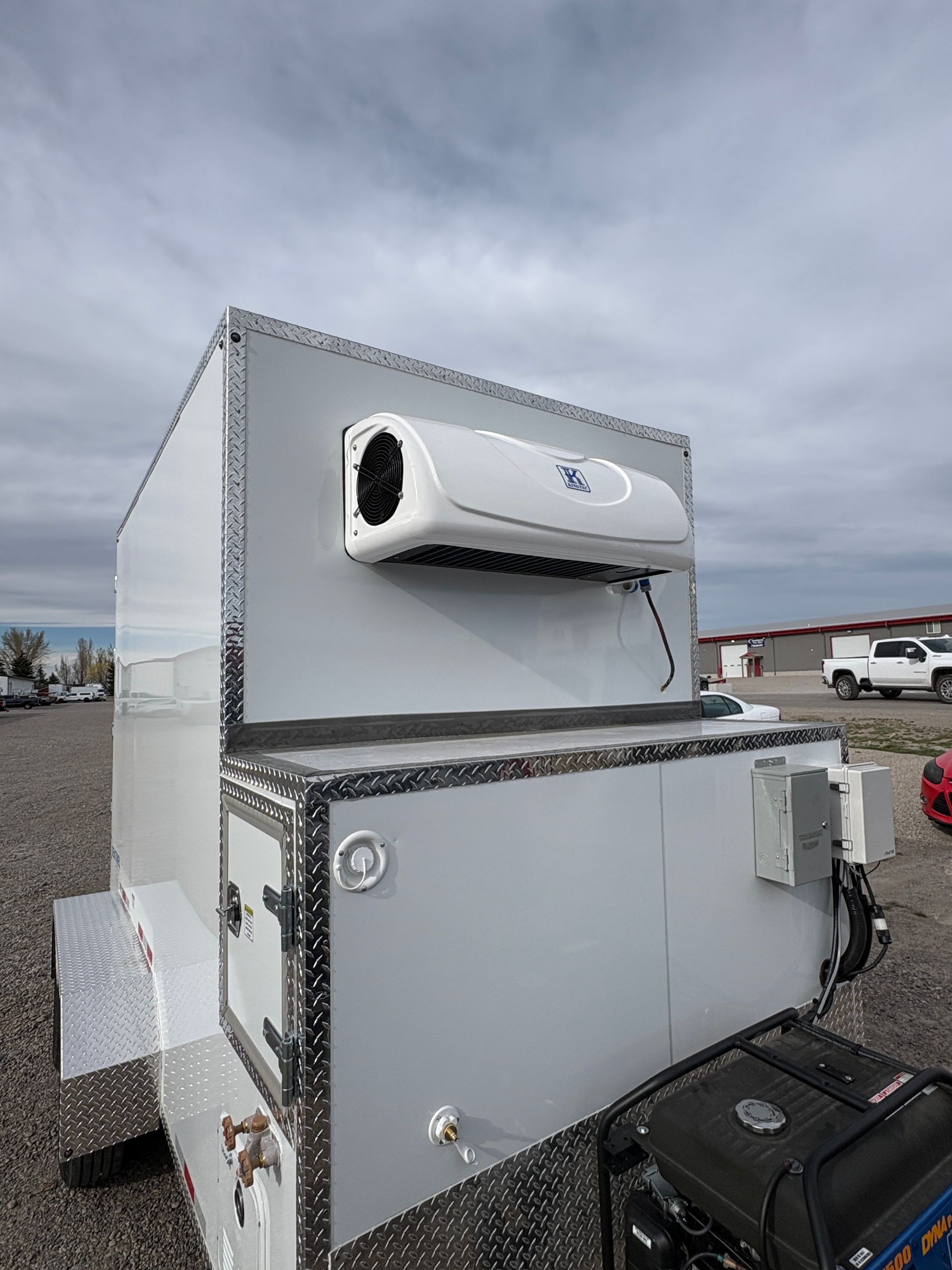 White industrial machine mounted on a trailer in a cloudy outdoor lot, with a black engine unit below.