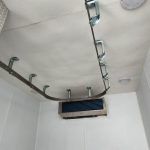 Ceiling-mounted metal track with hooks in a Sentinel trailer above a small window