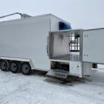 White butcher semi-trailer with open gut compartment hatch in a snowy lot