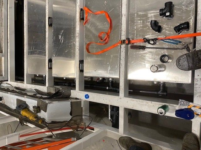 Open equipment panel with wiring, metal frames, and attached components inside a workspace