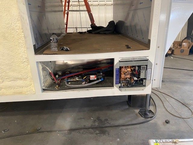 Open electrical panel built into a Sentinel Trailer with exposed wiring and tools on a concrete floor.