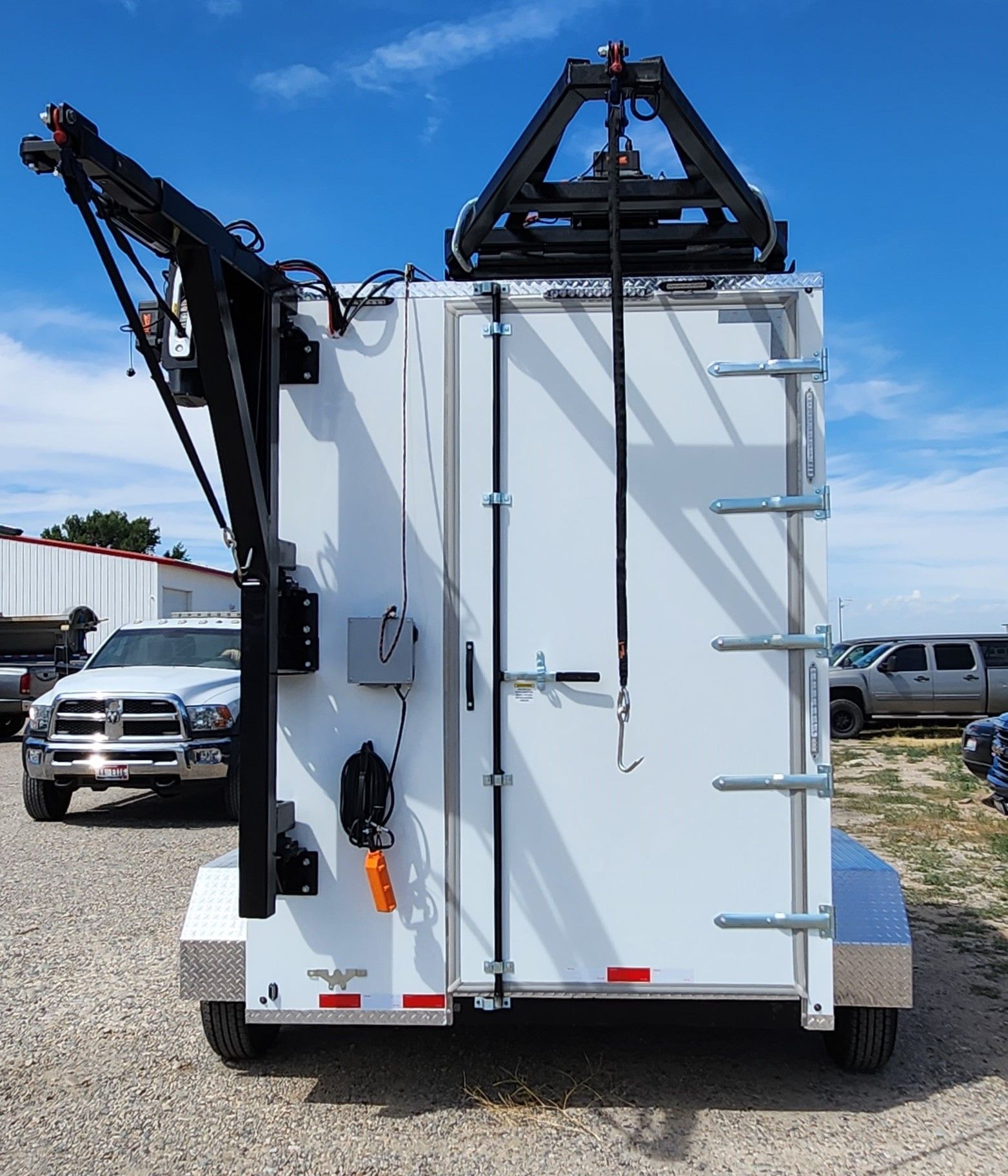 Rear view of a white utility truck with mounted crane equipment parked outdoors.