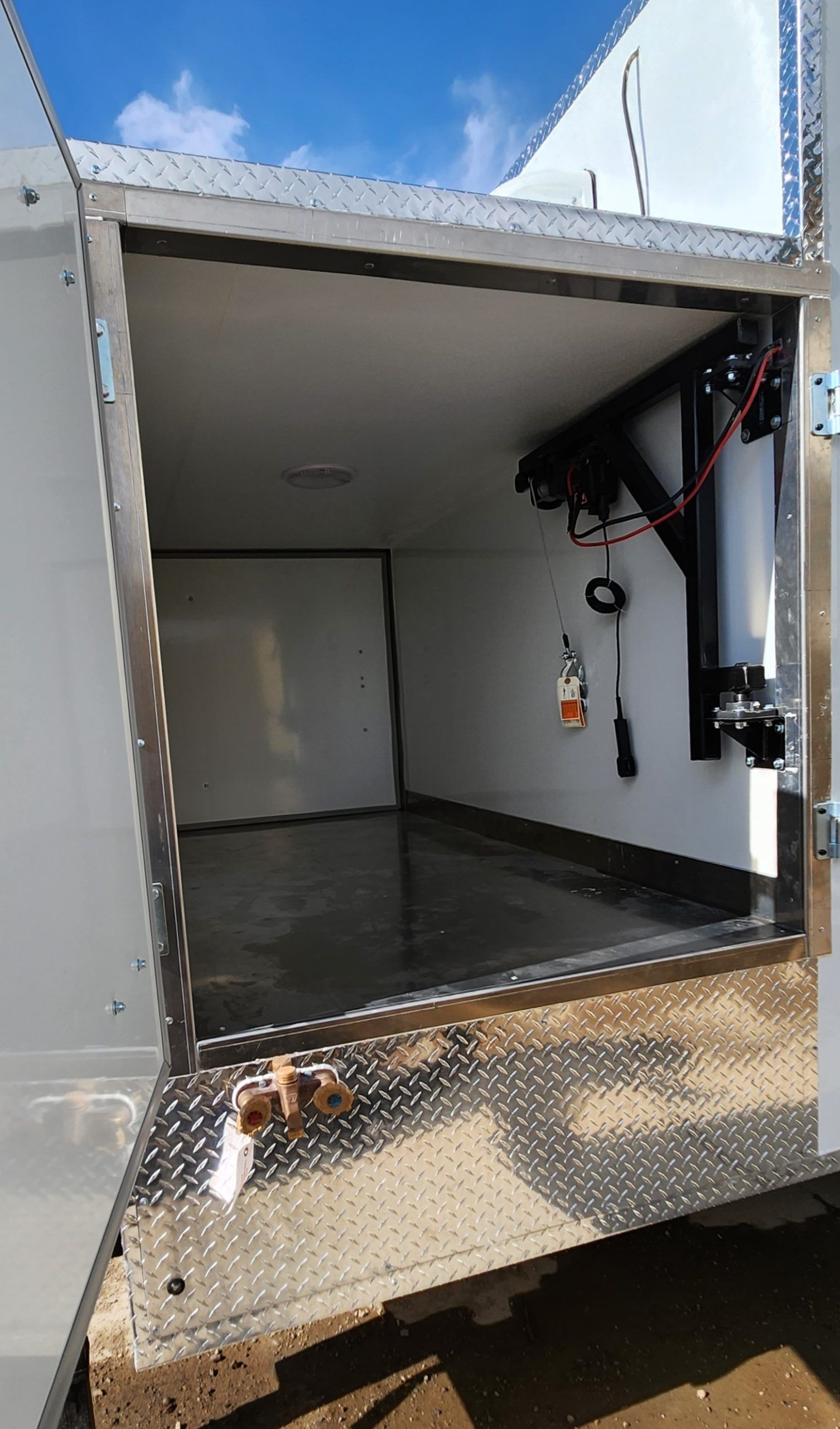 Open metal gut compartment of mobile slaughter trailer and equipment mounted on the right wall