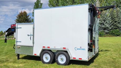 White enclosed refrigerated trailer with double axles parked on grass in a sunny outdoor setting