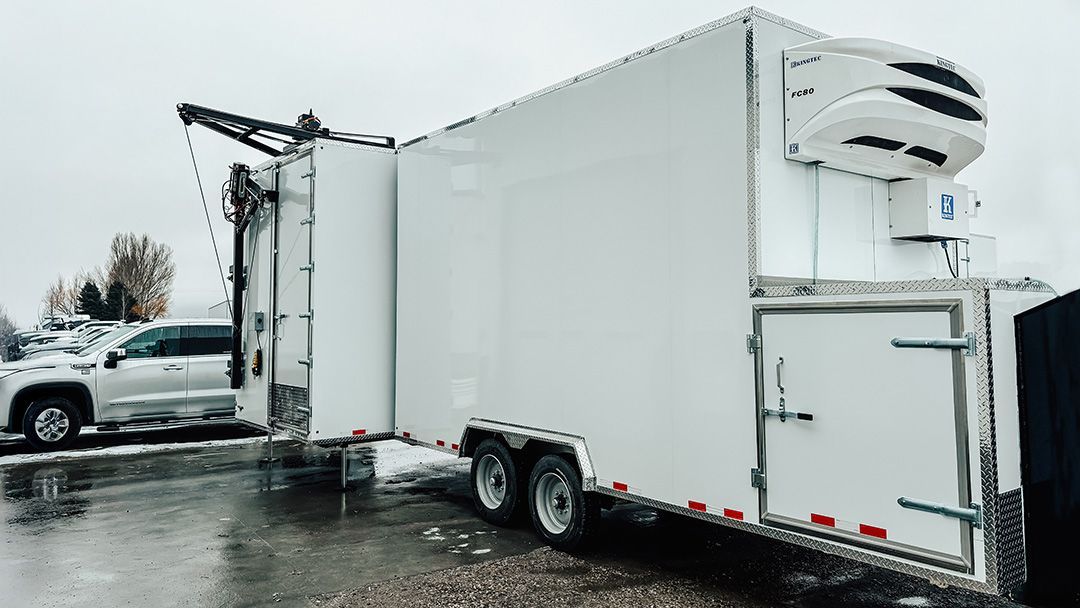 White refrigerated trailer truck parked on a wet lot in snowy weather