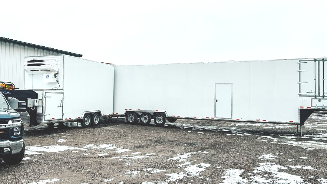 White refrigerated trailer for butcheres truck parked on a wet lot in snowy weather