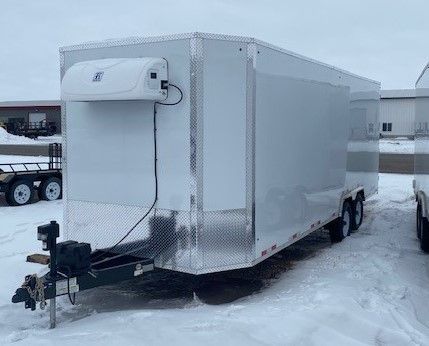 White enclosed trailer for slaughtering parked on snowy ground with a front-mounted unit and hitch visible