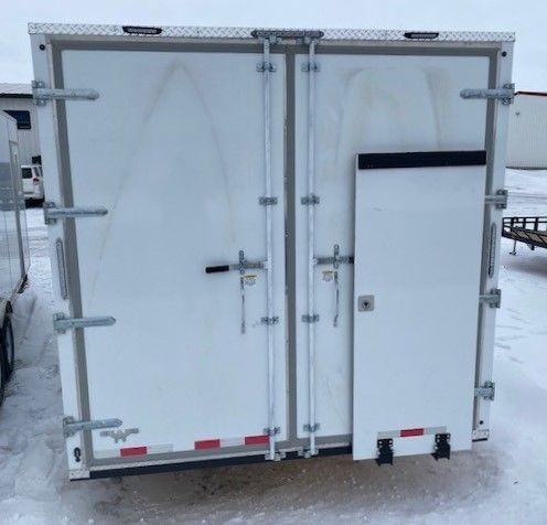 White Sentinel  utility trailer with double rear doors and a side access door parked on snowy ground.