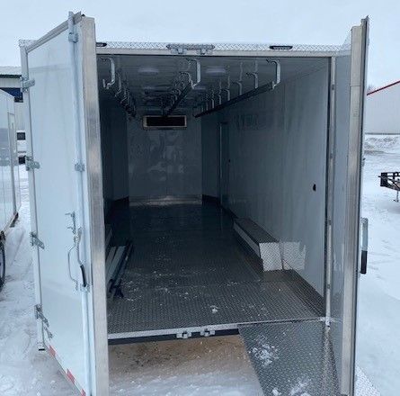 Open walk-in white refrigerated trailer with metal floor and hanging rails inside, viewed from the rear.