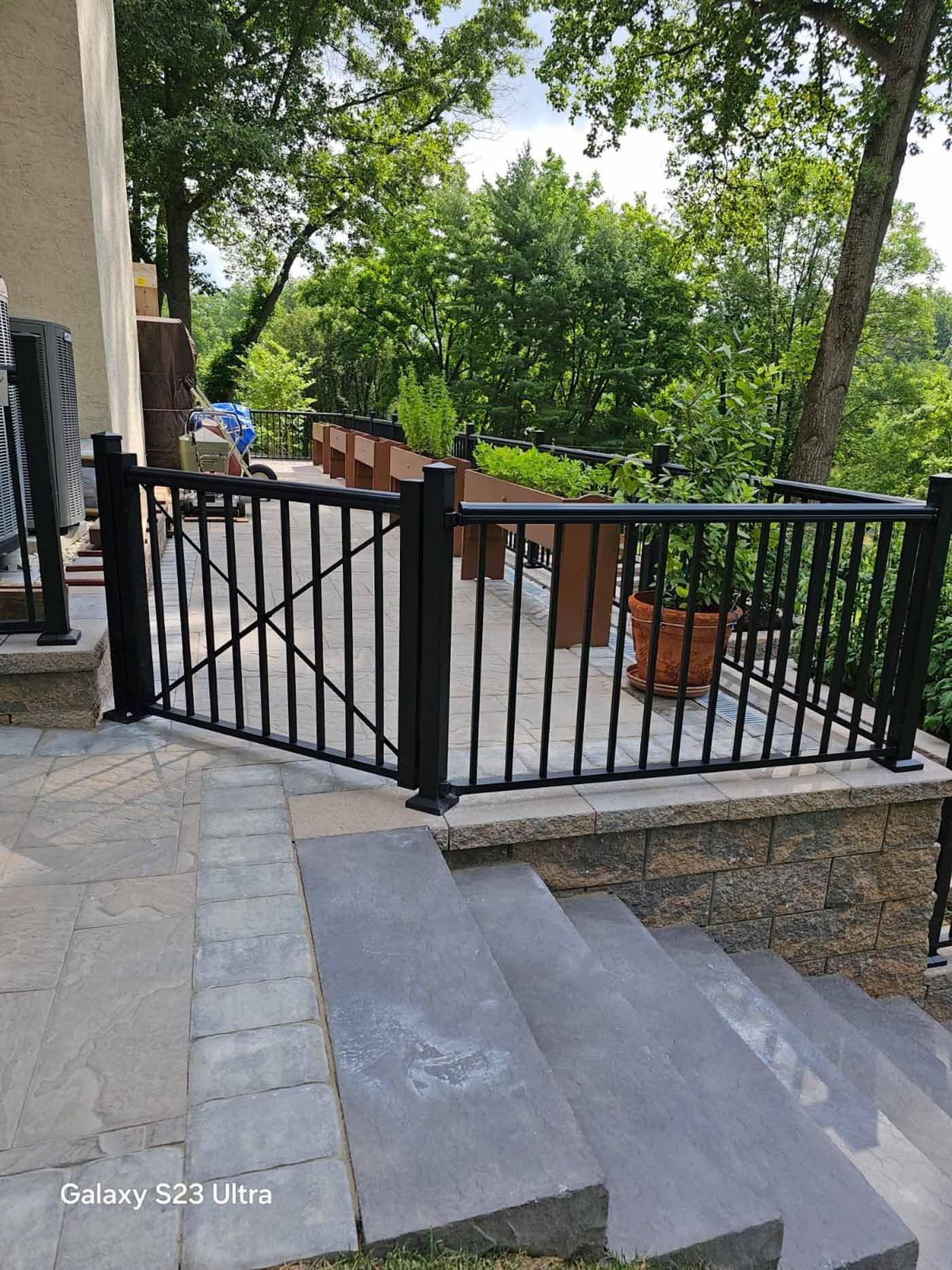 A black fence surrounds a patio with stairs leading up to it.