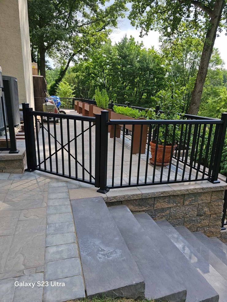 A black fence surrounds a patio with stairs leading up to it.