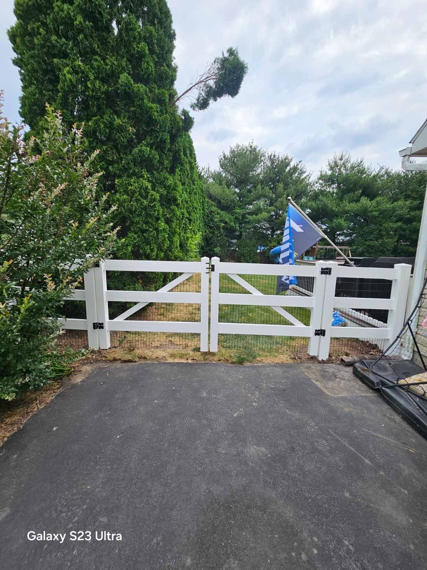 A man is standing in front of a wooden fence in a backyard.