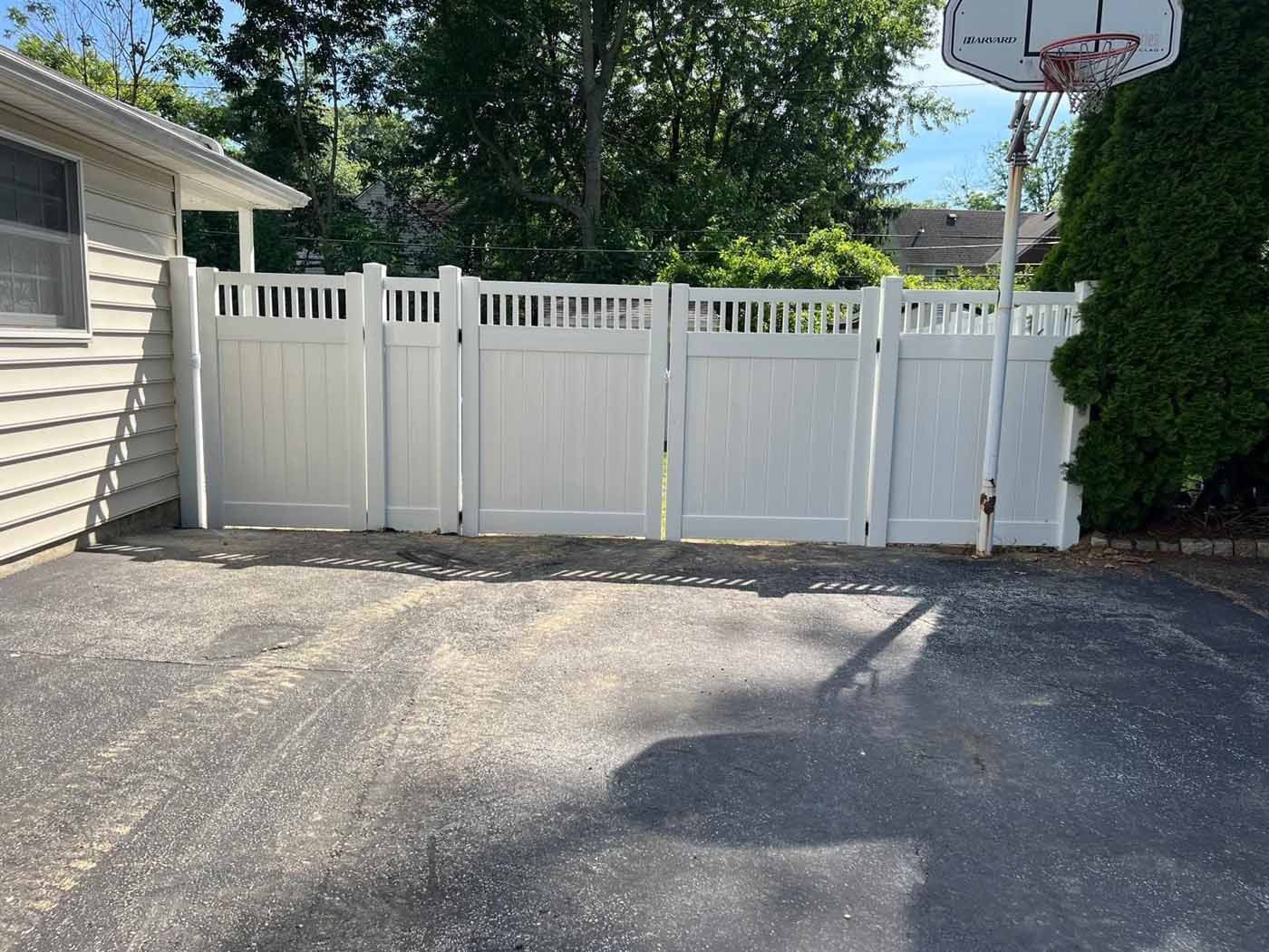 A man is standing in front of a wooden fence in a backyard.
