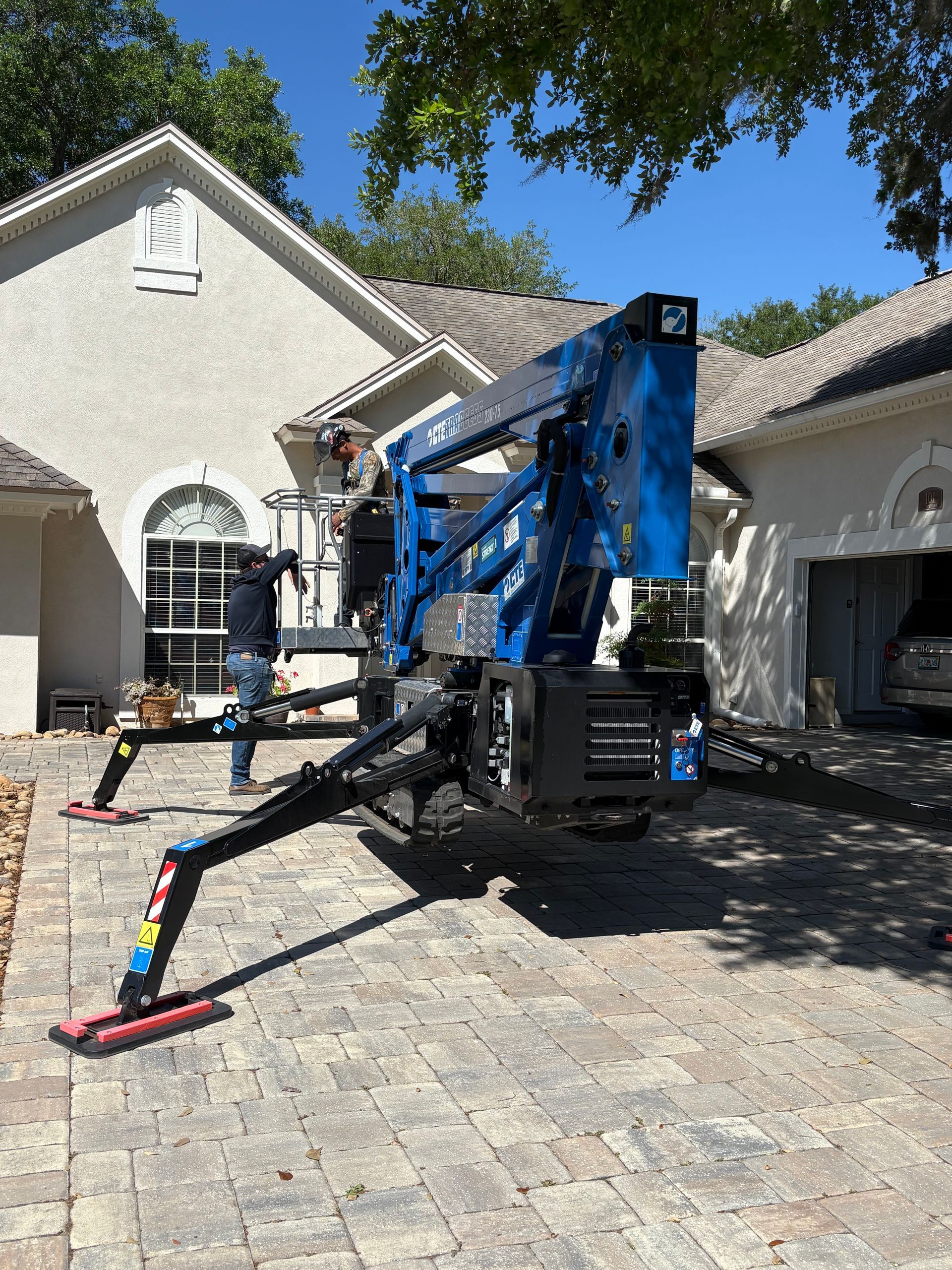 Blue aerial lift in front of a house. Two workers are present.