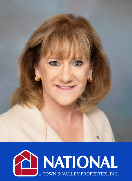 Kathy smiling in front of a national town and valley properties inc. logo .