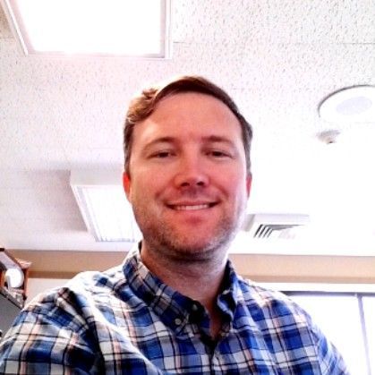 Nick Waldron in a plaid shirt is smiling for the camera .