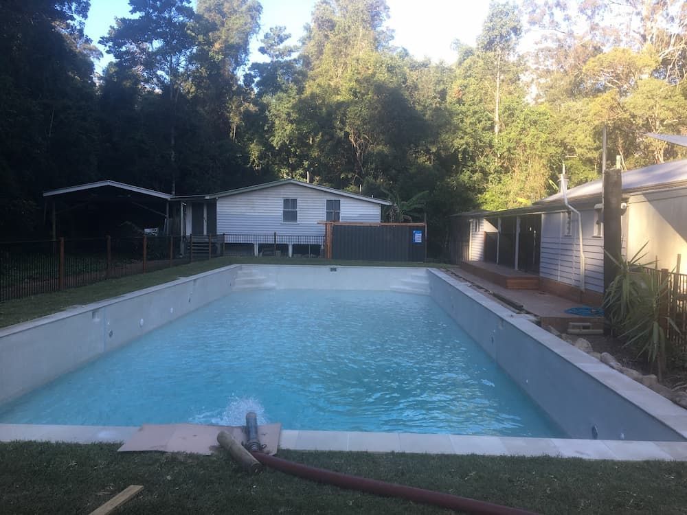 A Large Swimming Pool with A House in The Background — Stolzenberg Water Carriers in Curra, QLD