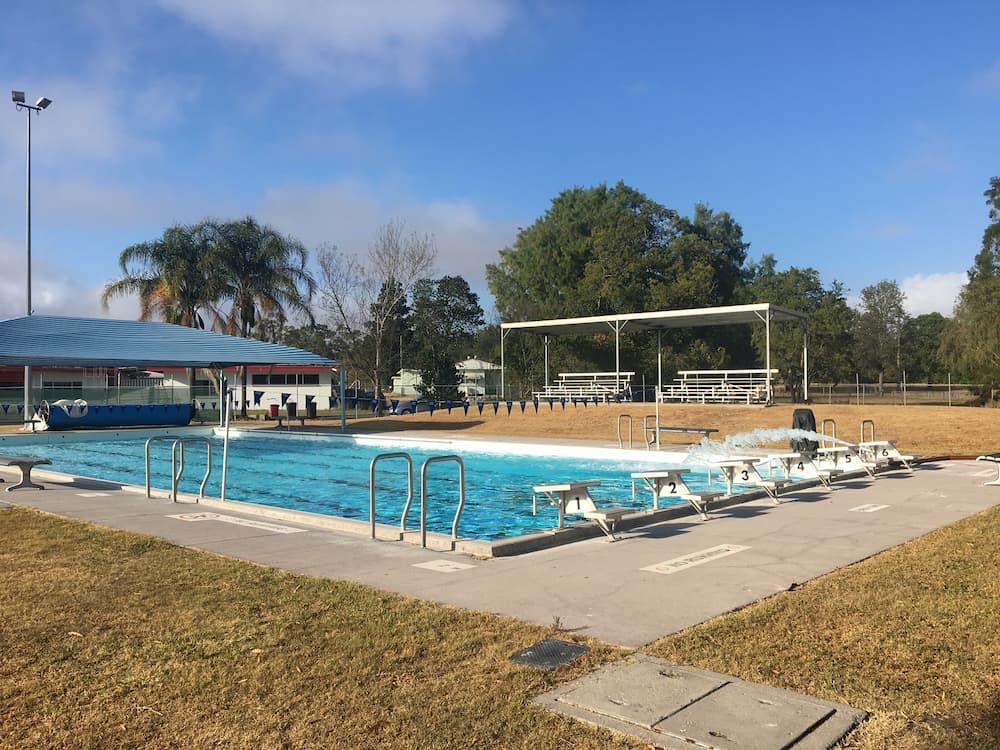 A Large Swimming Pool with A Volleyball Net in The Background — Stolzenberg Water Carriers in Gympie, QLD