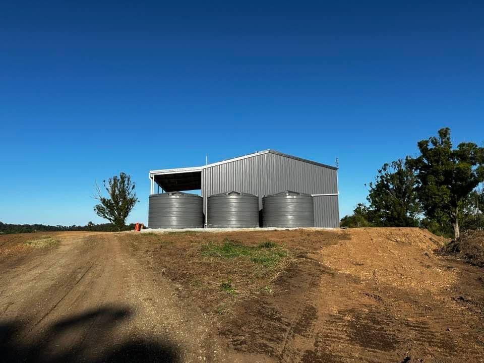 A Building with Three Water Tanks in Front of It Is Sitting on Top of A Dirt Hill — Stolzenberg Water Carriers in Curra, QLD