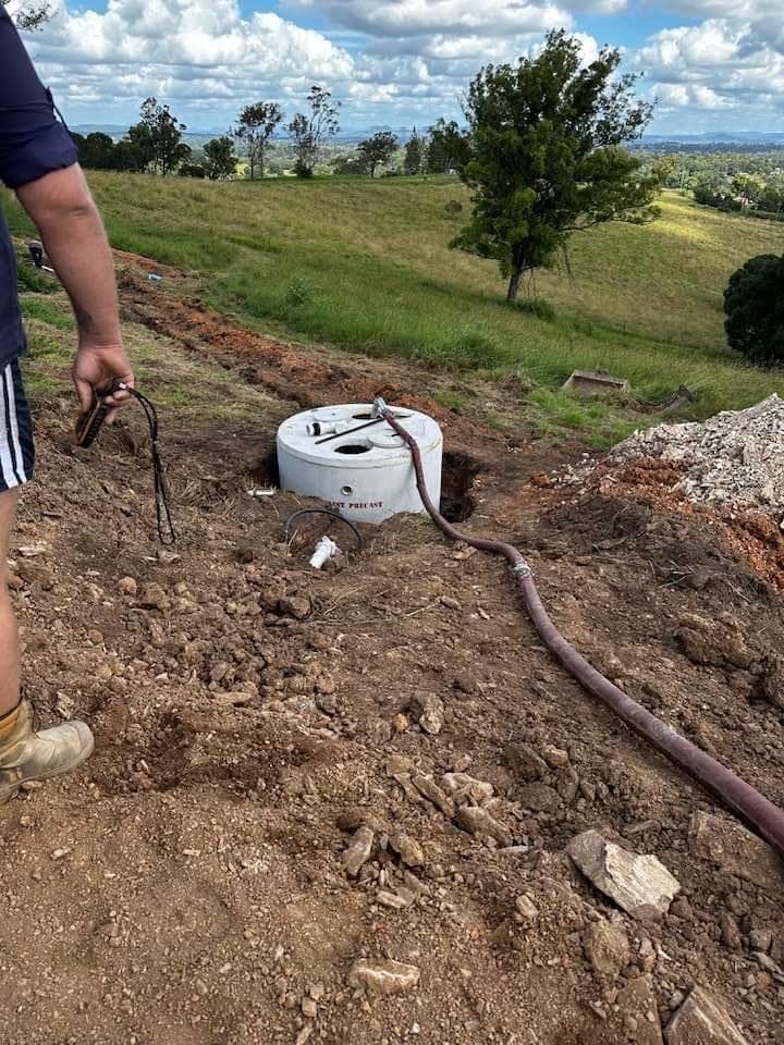 A Man Is Standing Next to A Manhole Cover in The Dirt — Stolzenberg Water Carriers in Curra, QLD