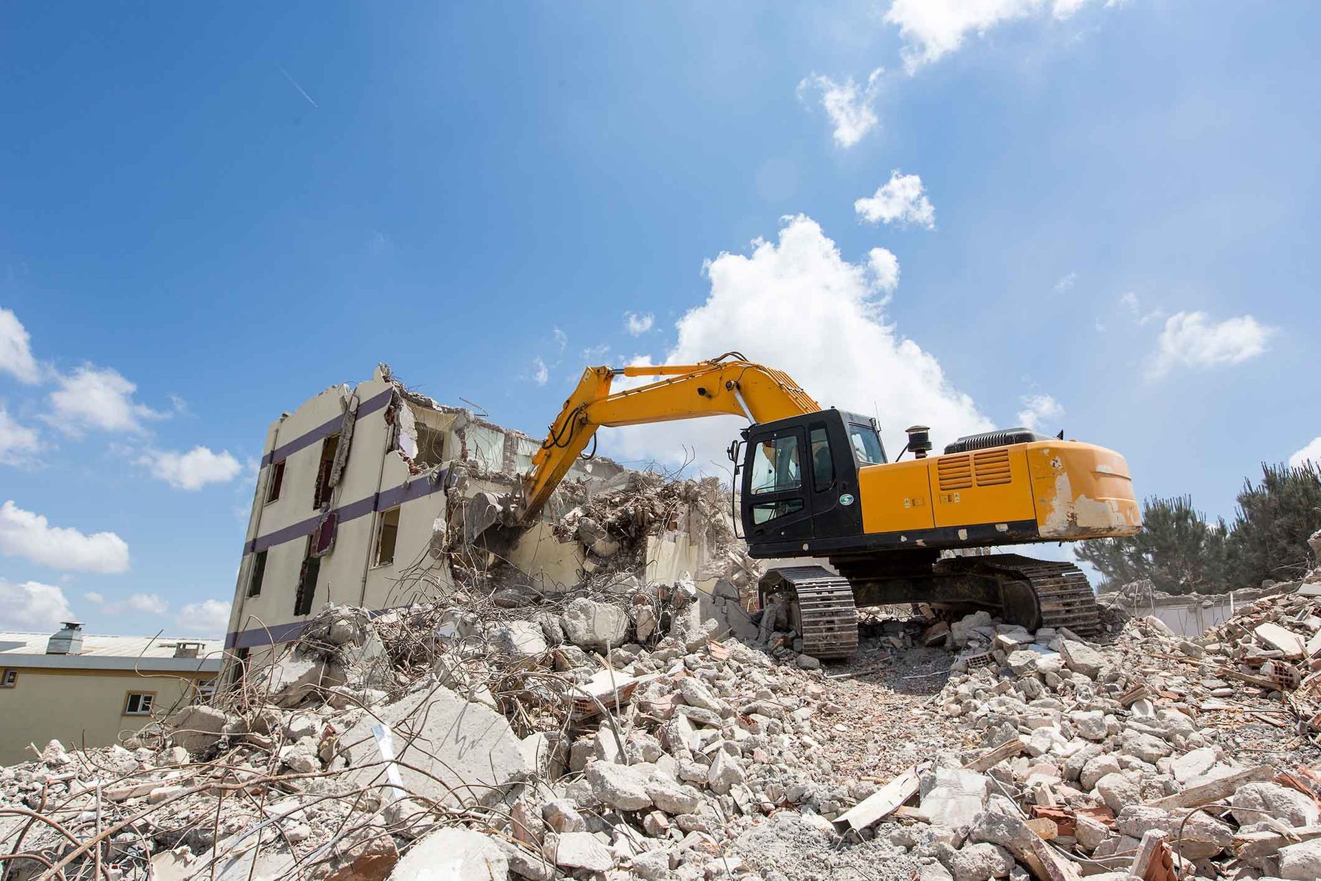 A Large Yellow Excavator Is Demolishing A Building – Port Pirie, SA - Flinders Earthmoving & Blue Metal Supplies