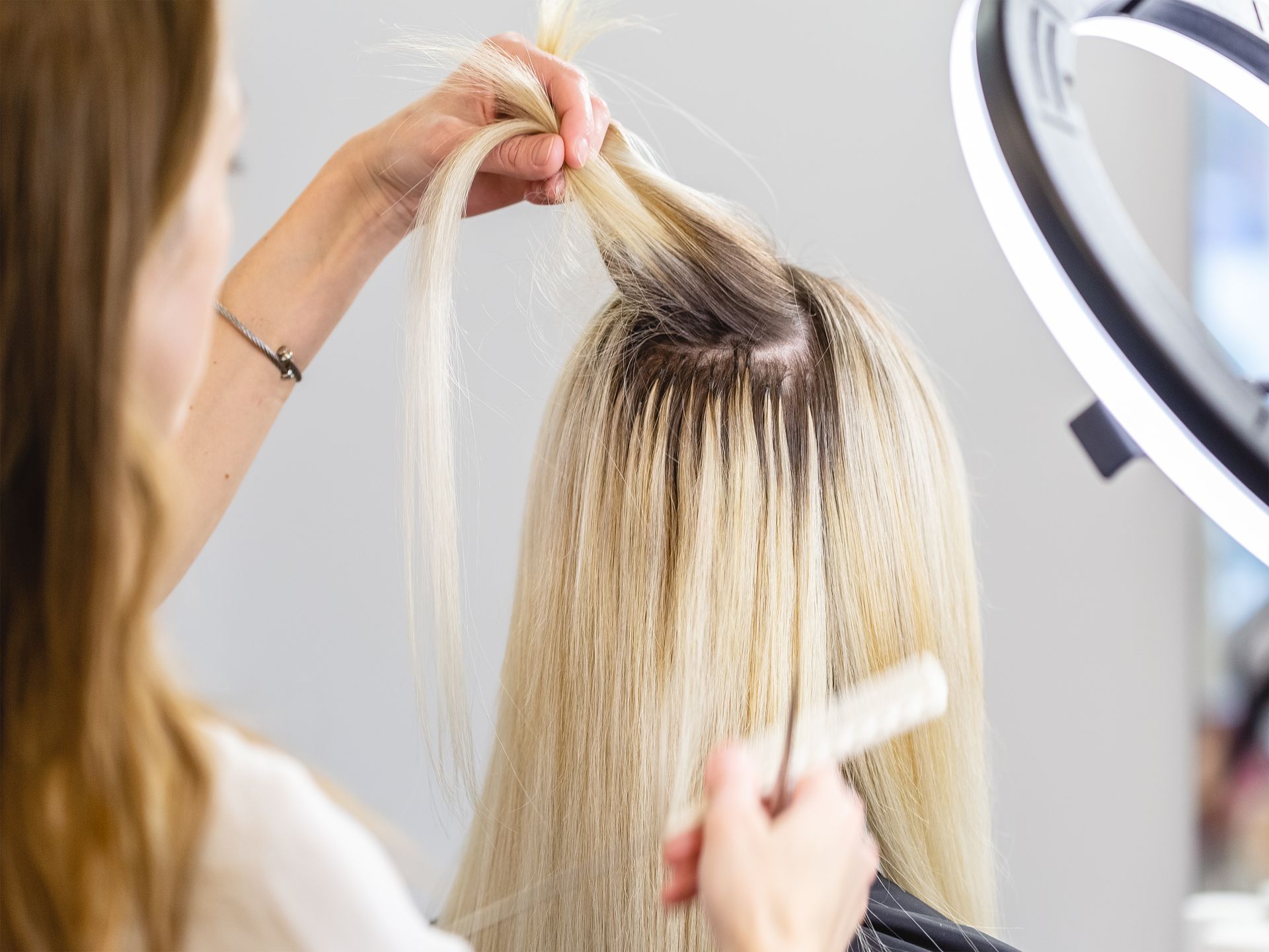 Hairdresser Applying Blonde Hair Extensions to a Client's Head — Southside Hair & Beauty Design In South Tamworth, NSW