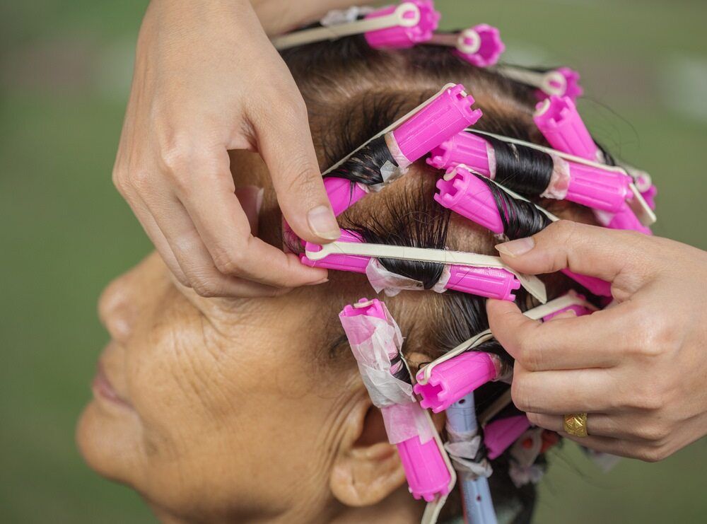 A Woman is Getting Her Hair Curled With Pink Curlers — Southside Hair & Beauty Design In South Tamworth, NSW