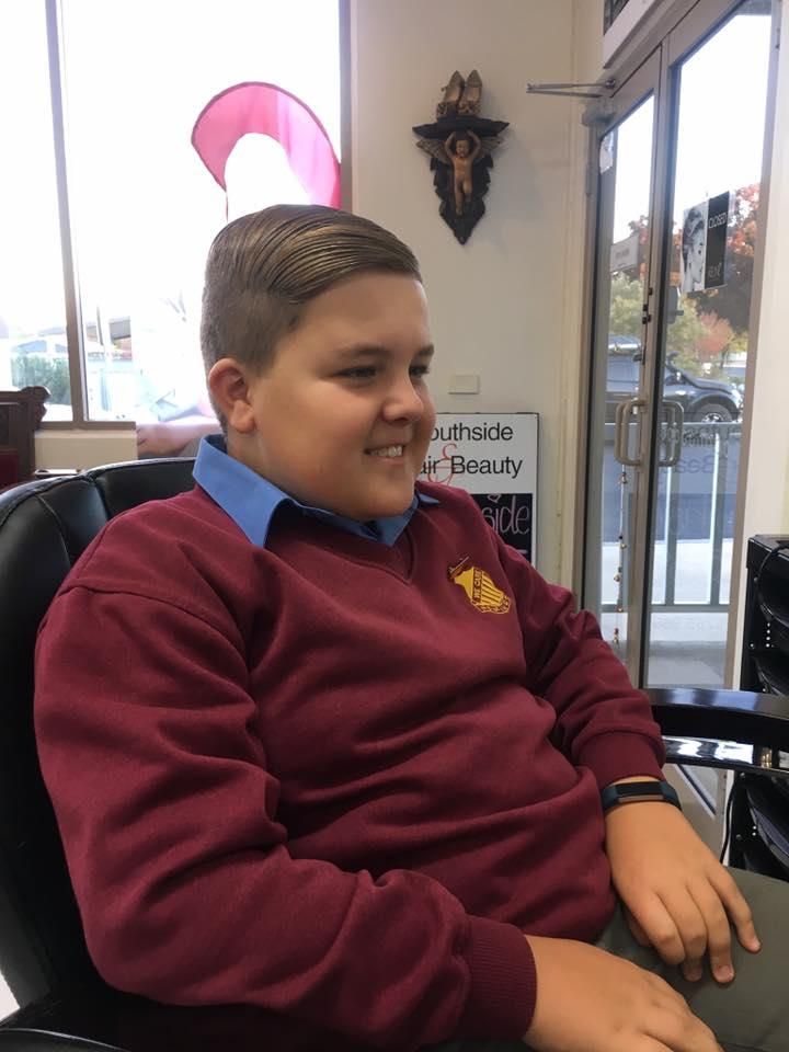 A Boy in a Maroon Sweater is Sitting in a Chair — Southside Hair & Beauty Design In South Tamworth, NSW