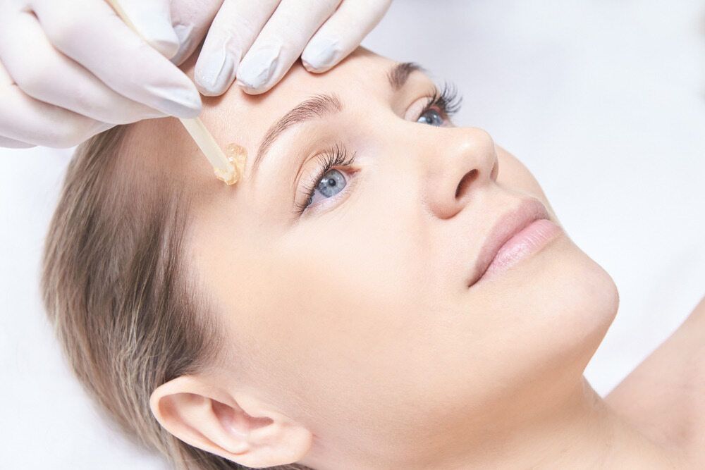 Person Getting Eyebrow Waxed; Gloved Hands Apply Wax to Brow — Southside Hair & Beauty Design In South Tamworth, NSW