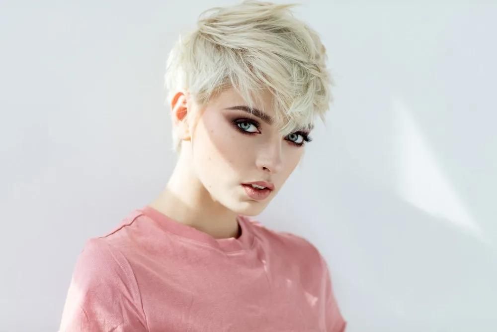 A Woman With Short Blonde Hair is Wearing a Pink Shirt and Looking at the Camera — Southside Hair & Beauty Design In South Tamworth, NSW A Woman With Short Blonde Hair is Wearing a Pink Shirt — Southside Hair & Beauty Design In South Tamworth, NSW
