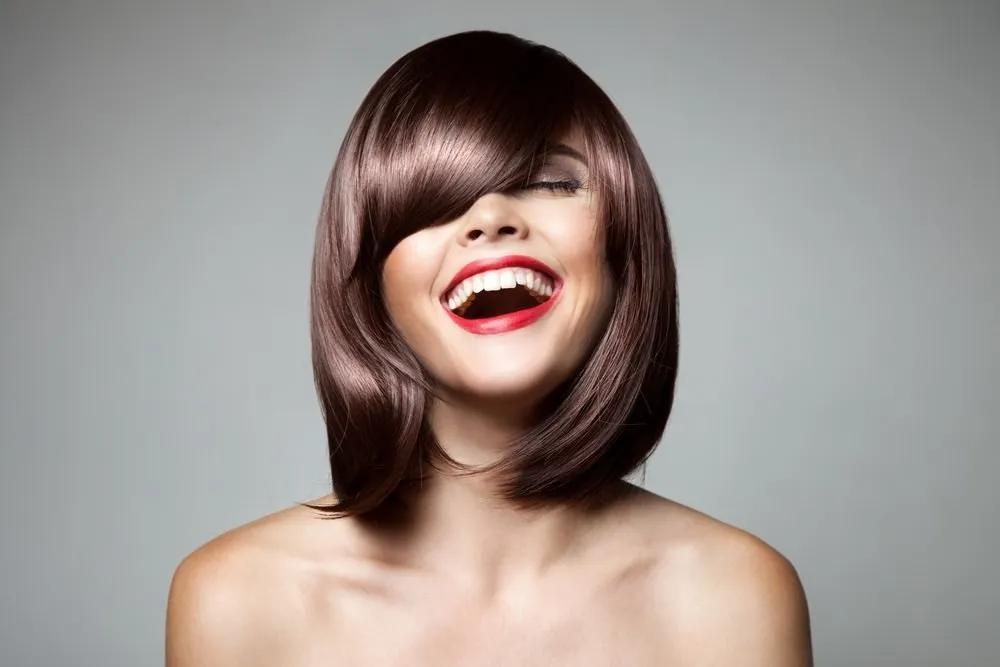 A Woman With Long Brown Hair is Smiling With Her Mouth Open — Southside Hair & Beauty Design In South Tamworth, NSW
