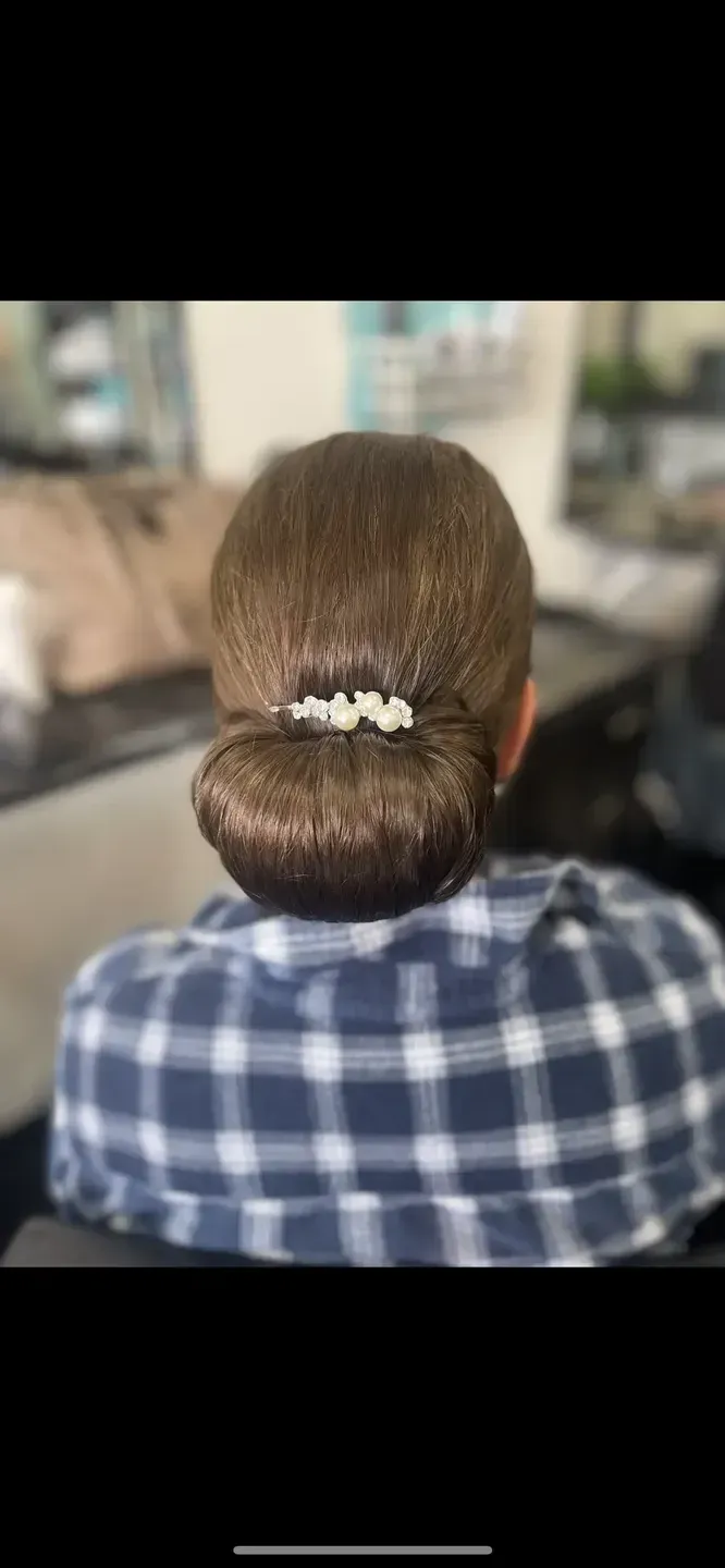 A woman is sitting in a chair with her hair in a bun — Southside Hair & Beauty Design In South Tamworth, NSW