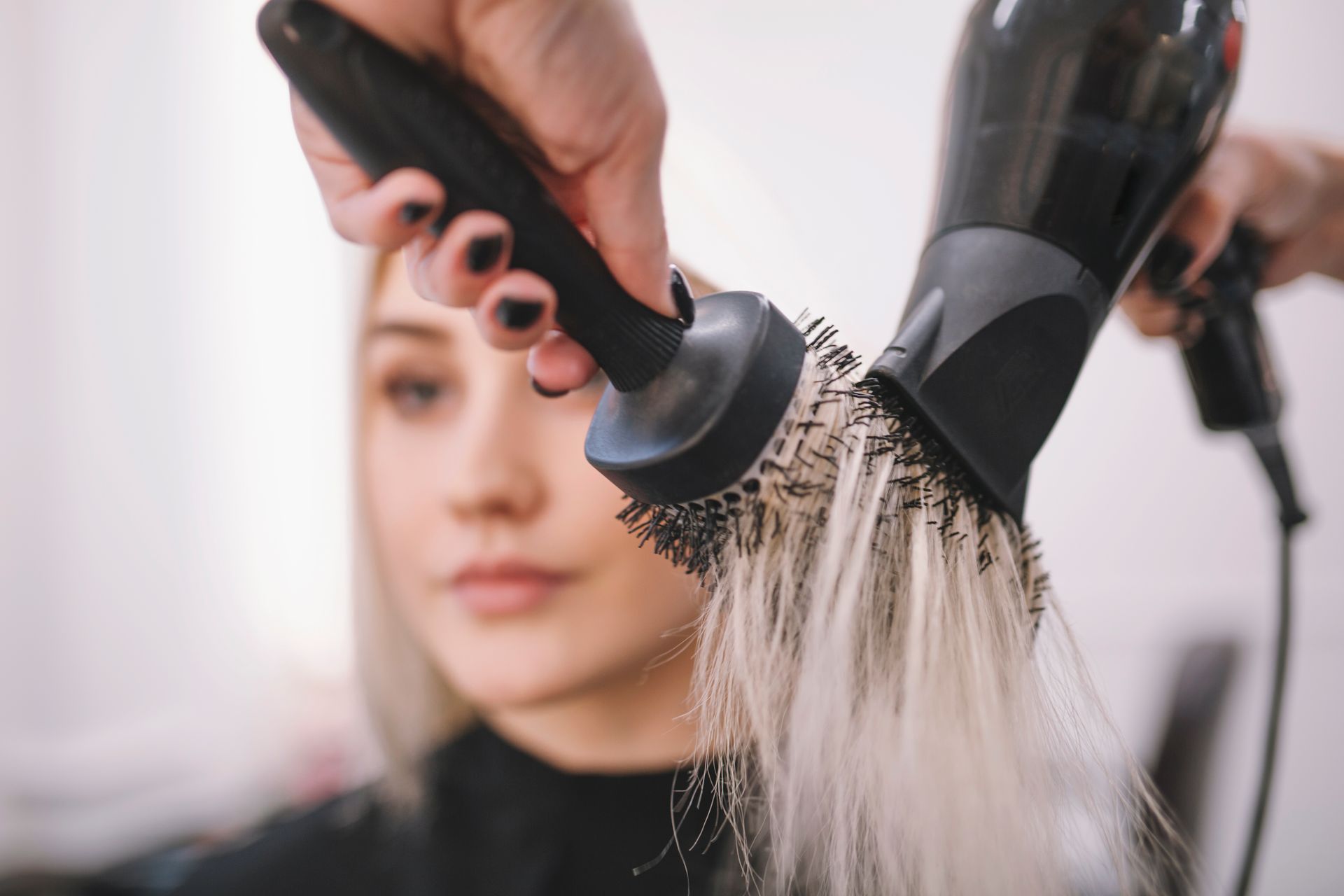 Hairdresser blow-drying a client's wet hair in a salon. The client is seated, wearing a protective cape — Southside Hair & Beauty Design In South Tamworth, NSW