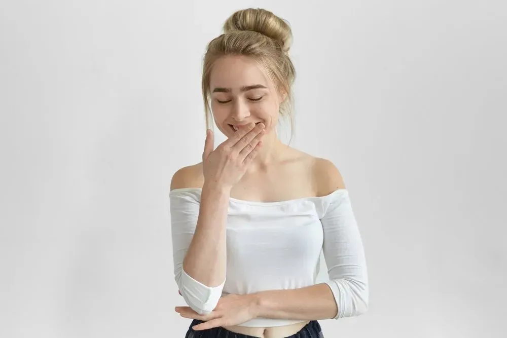 A Woman is Covering Her Mouth With Her Hand and Smiling — Southside Hair & Beauty Design In South Tamworth, NSW