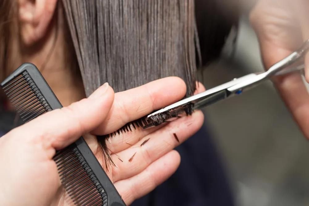 A Woman is Getting Her Hair Cut by a Hairdresser — Southside Hair & Beauty Design In South Tamworth, NSW