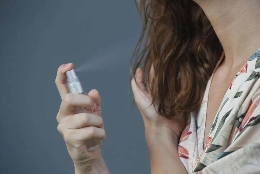 A Woman is Spraying Perfume on Her Arm — Southside Hair & Beauty Design In South Tamworth, NSW