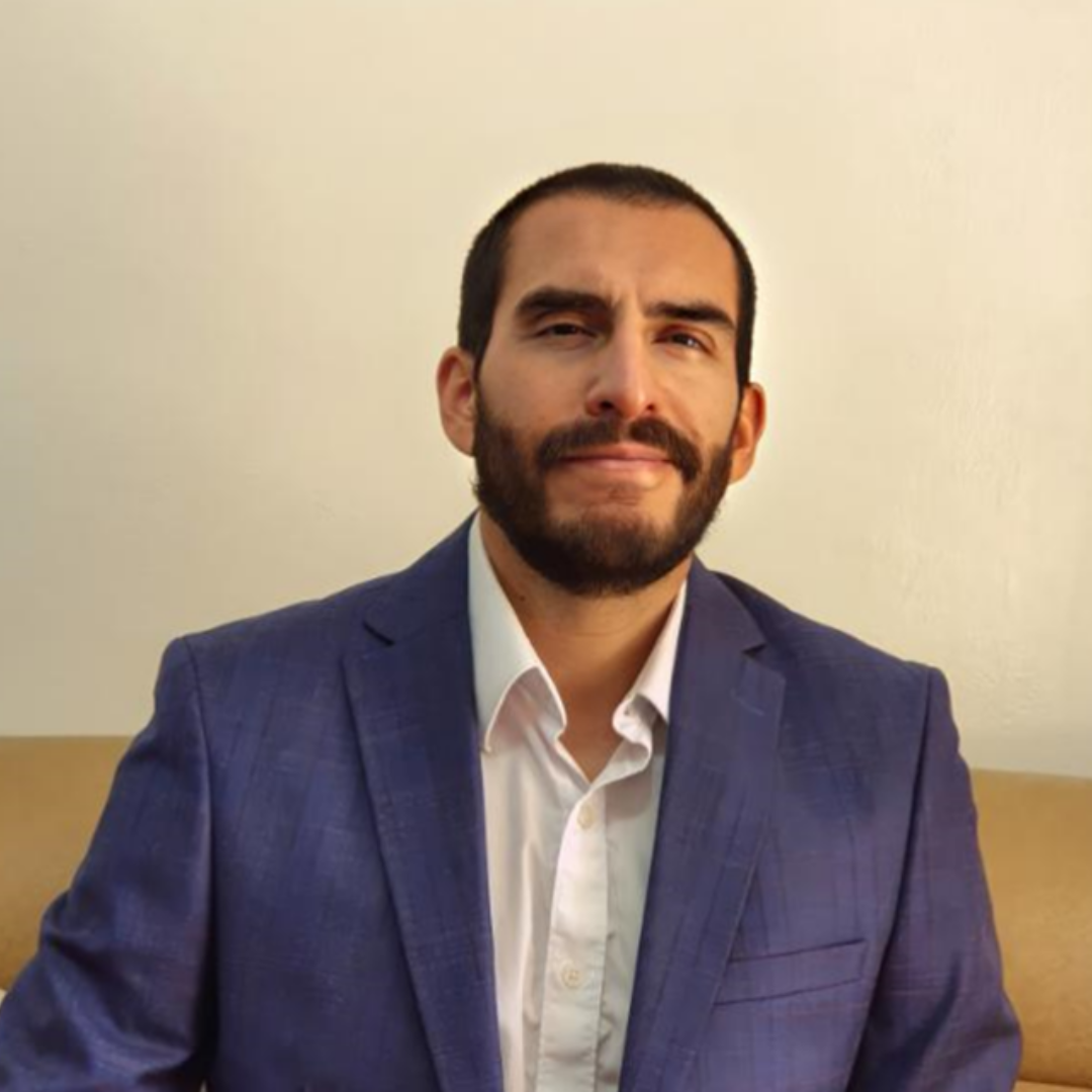 Un hombre con barba lleva un traje azul y una camisa blanca.