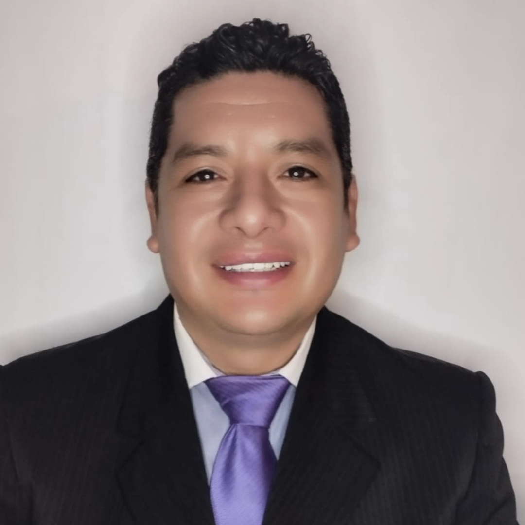 Un hombre con traje y corbata sonríe a la cámara.