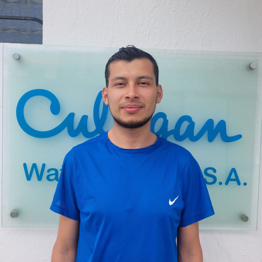 Un hombre con una camisa azul se encuentra frente a un cartel que dice Culligan.