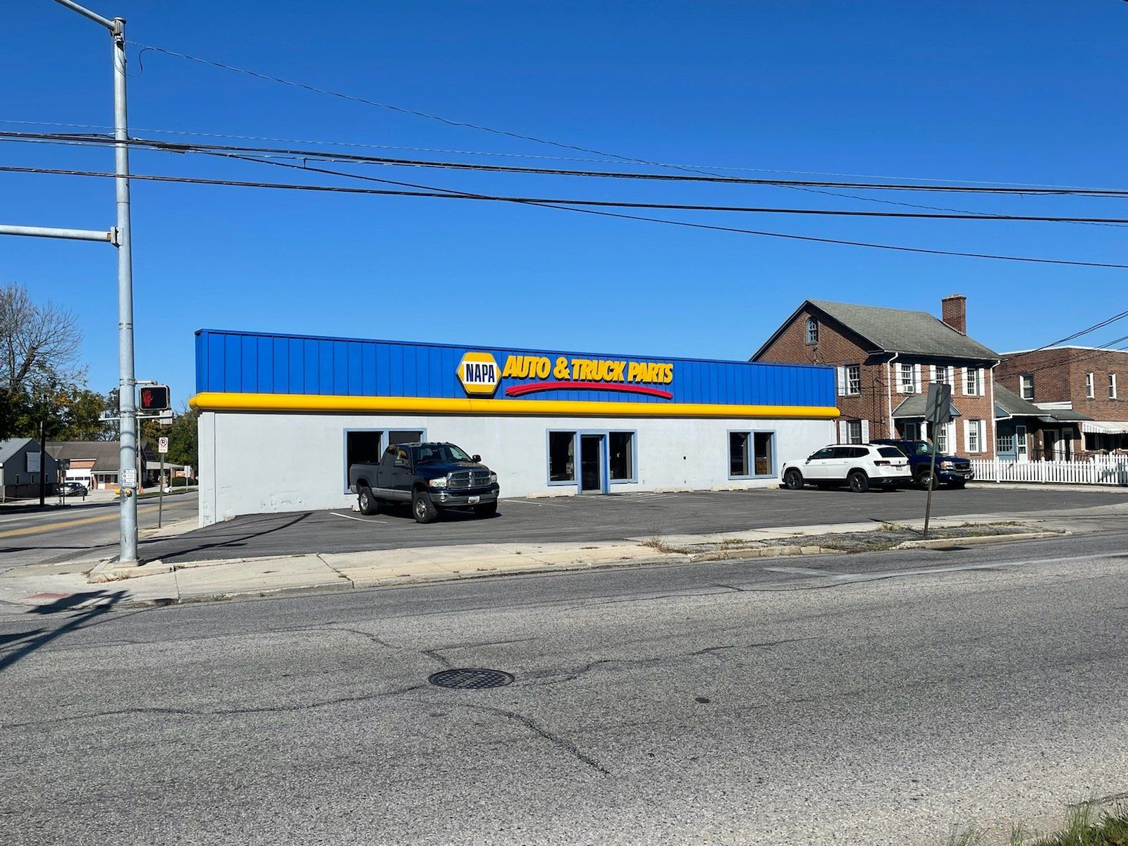 NAPA Auto Parts store with blue and yellow facade, black truck parked out front, on a sunny day.