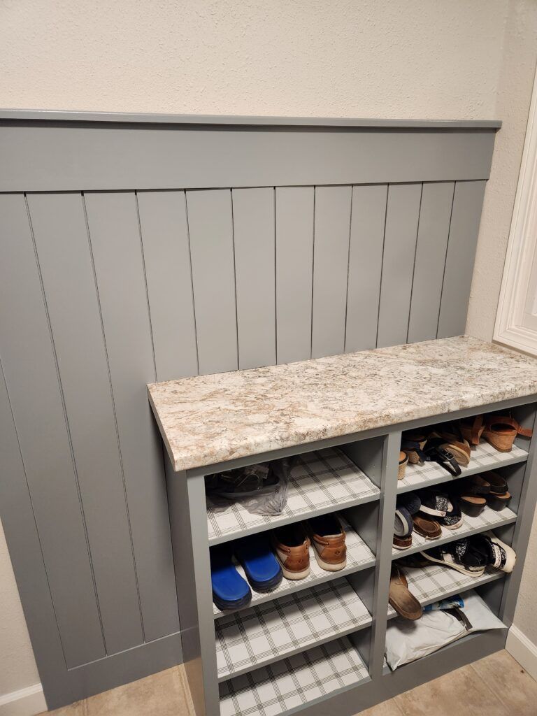 A shoe rack with a granite counter top in a room.
