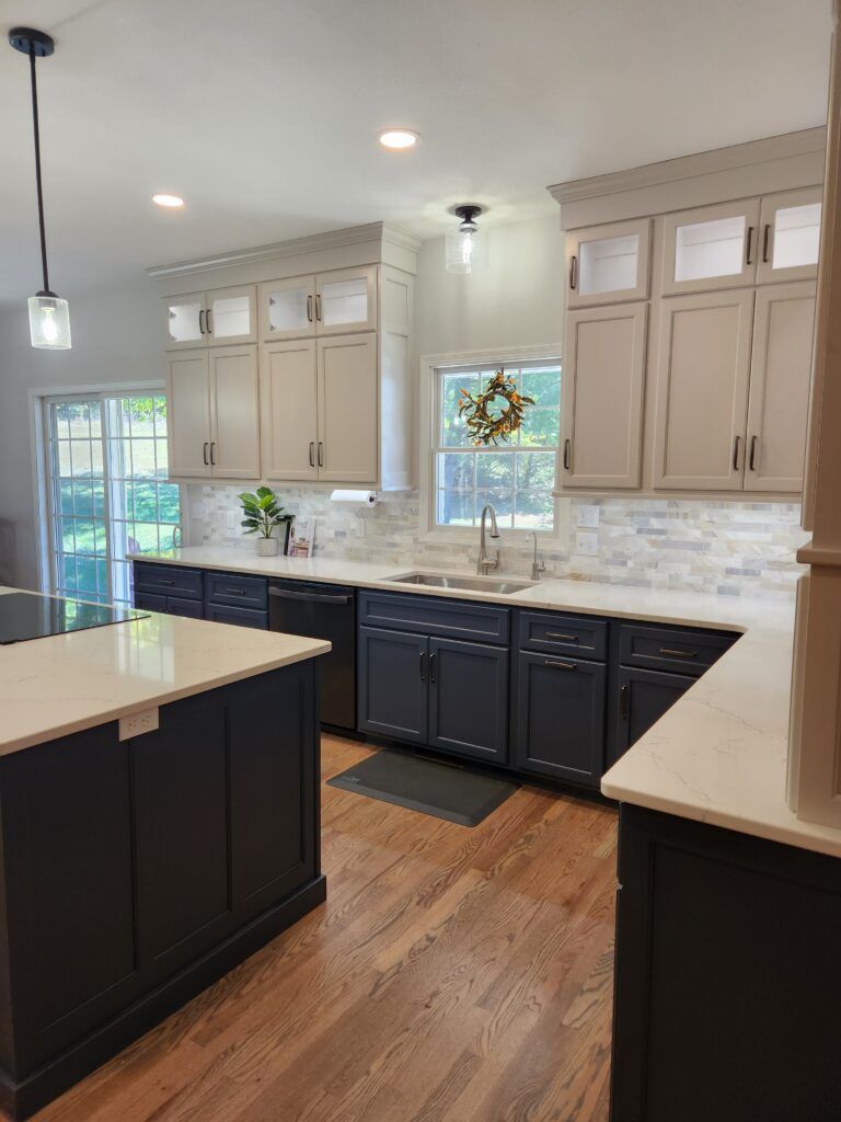 A kitchen with blue cabinets , white counter tops , a sink and a window.