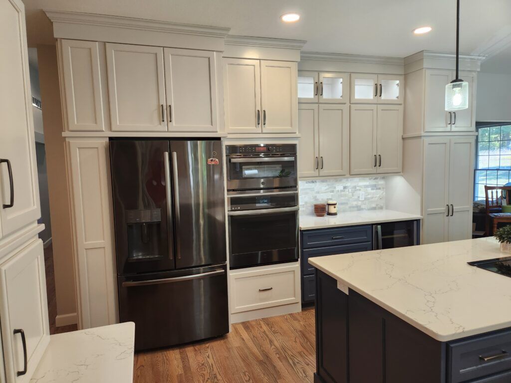 A kitchen with white cabinets , stainless steel appliances , and a large island.