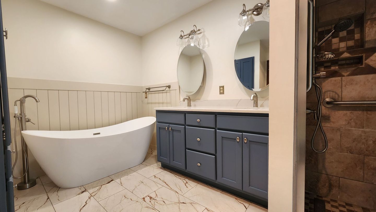 A bathroom with a bathtub , two sinks , and two mirrors.