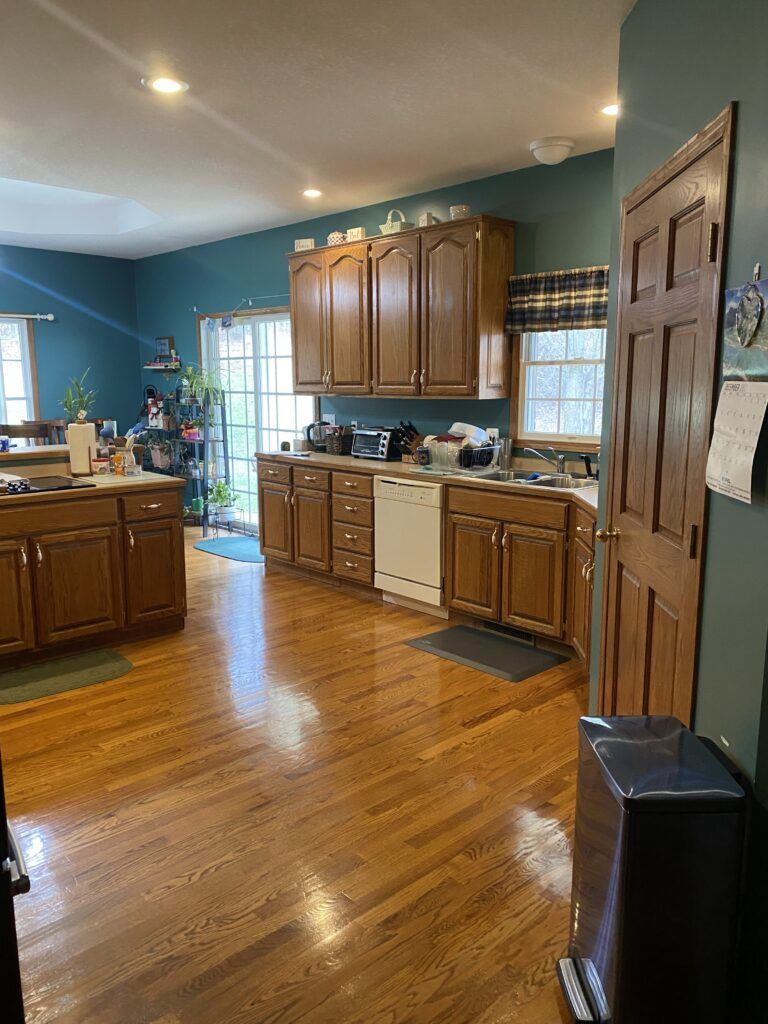 A kitchen with wooden cabinets , hardwood floors , a sink , and a dishwasher.