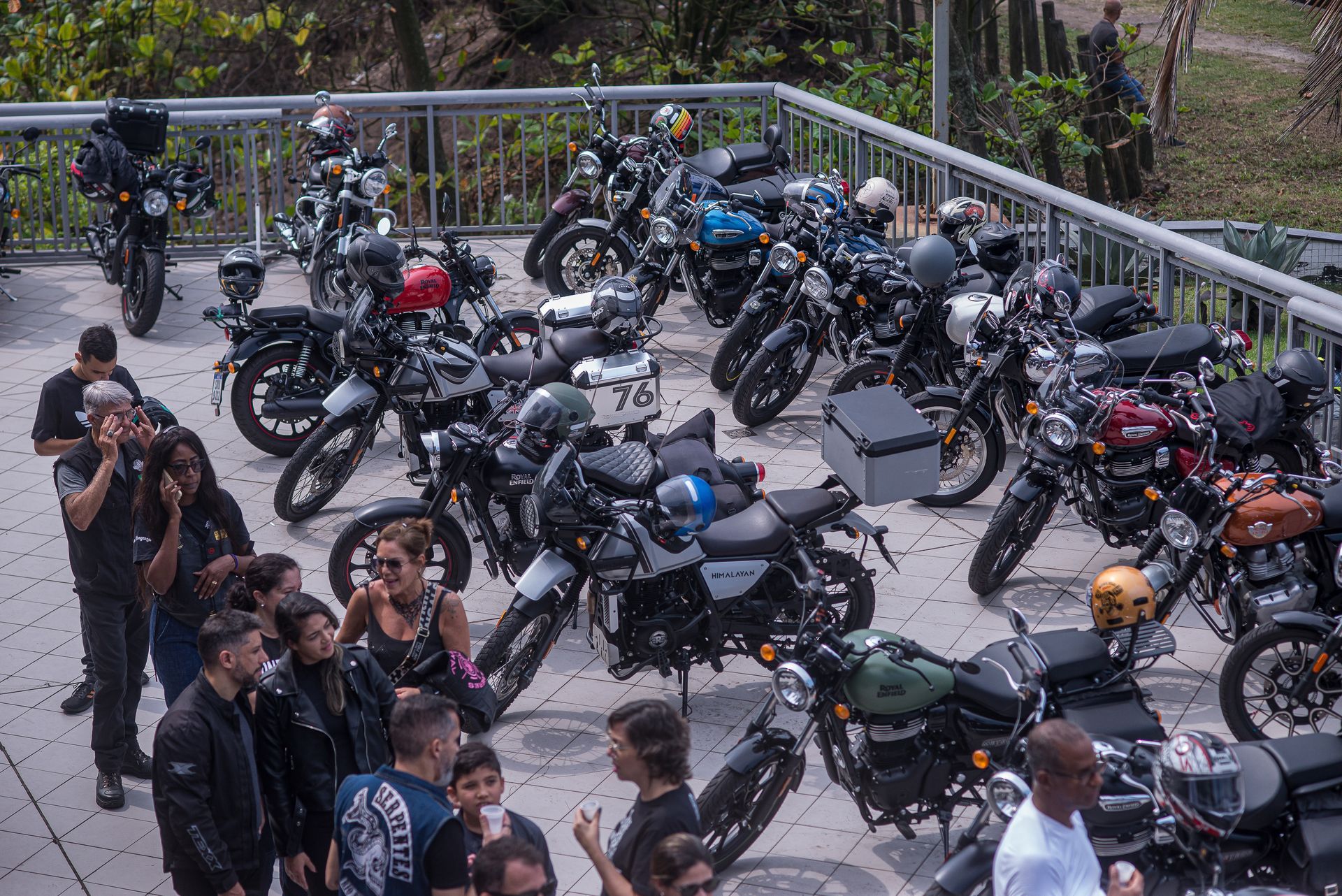Estacionamento lotado para motocicletas em um terraço, com muitas motos e várias pessoas em volta.