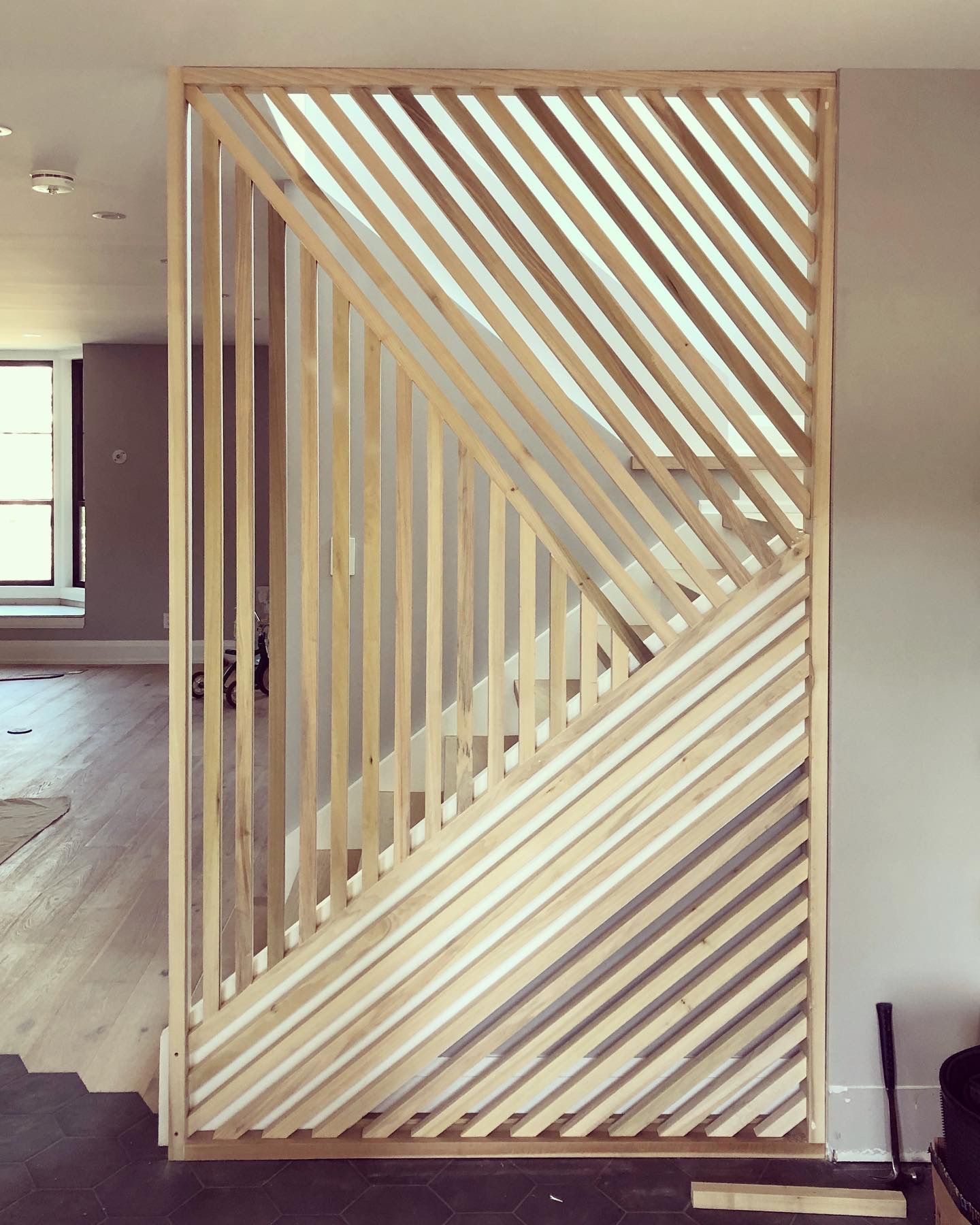 A wooden room divider with a staircase in the background.