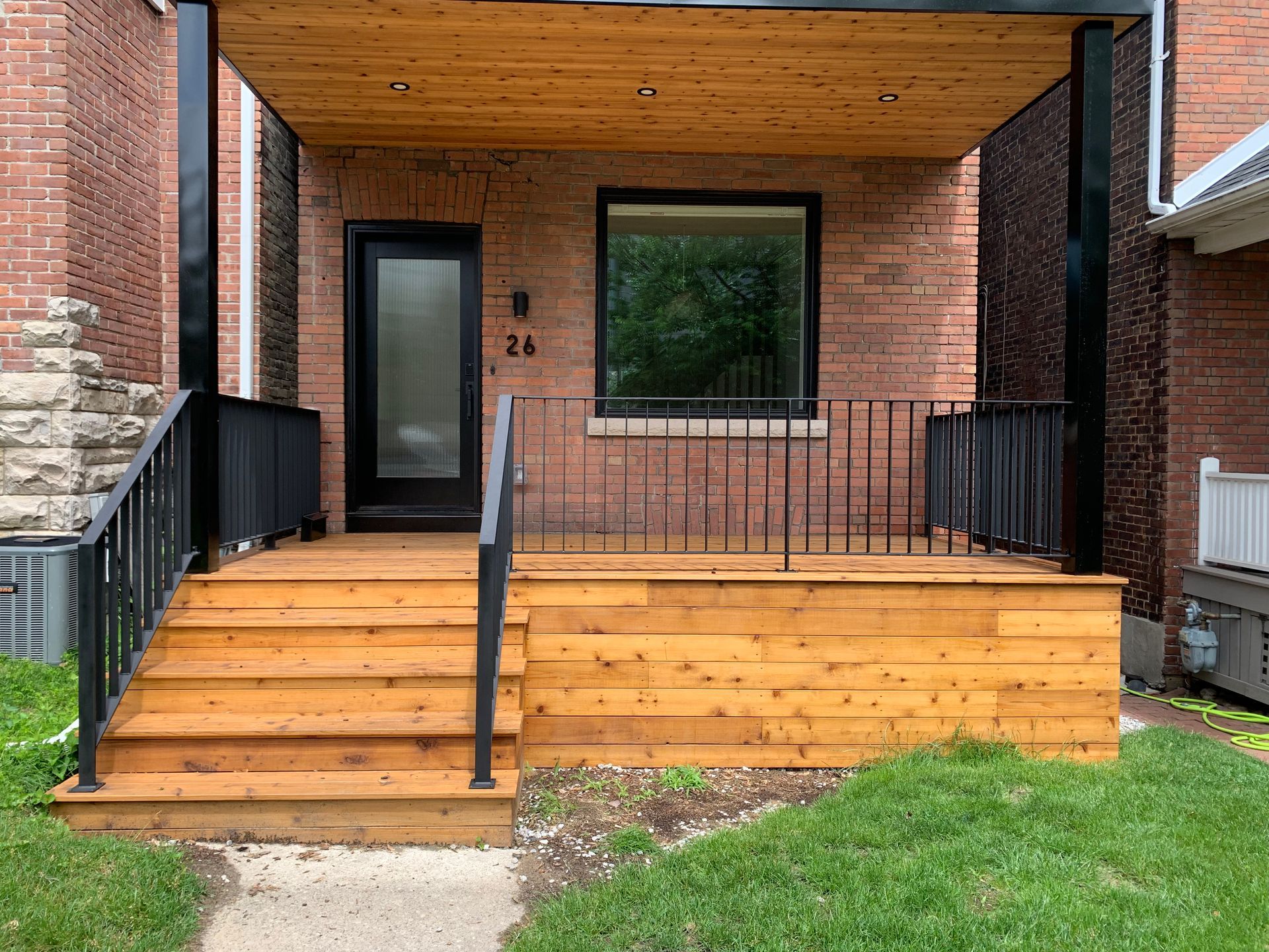 The front of a brick house with a wooden porch and stairs.