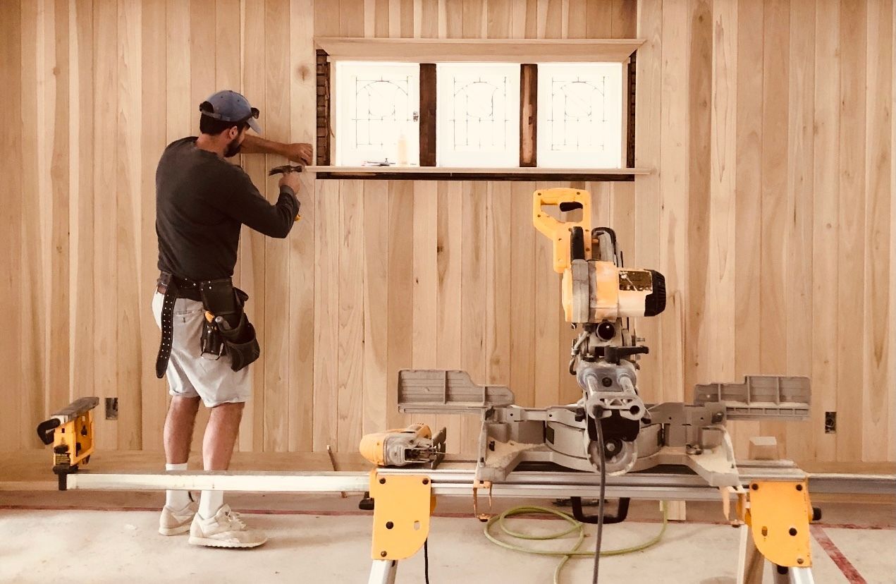 A man is standing next to a sliding saw in a room.